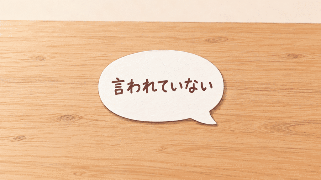 木の机の上に置かれた白い吹き出しの形の紙に、「言われていない」と書かれている図